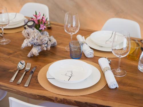 a wooden table with white plates and wine glasses at Giraud I - Luxurious secluded villa next to the sea in Lajares