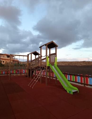a playground with a green slide on the beach at Giraud I - Luxurious secluded villa next to the sea in Lajares