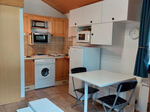 une petite cuisine avec une table et des chaises blanches dans l'établissement Charmant 2 pièces rénové avec balcon, wifi et parking, proche centre et commerces - FR-1-517-66, à Chamonix-Mont-Blanc