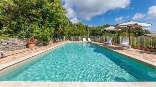 a swimming pool with chairs and an umbrella at Fresia in Sassetta