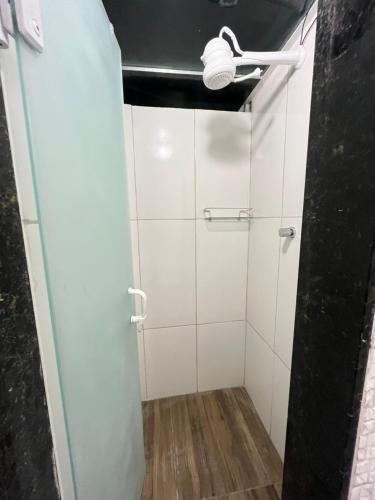 a bathroom with white tiles and a light on the ceiling at Cobertura a 5mts da Praia, Churrasqueira, Varandão, Ar condicionado in Cabo Frio