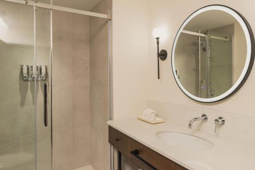 a bathroom with a shower and a sink and a mirror at Hotel Chateau Laurier Québec in Quebec City