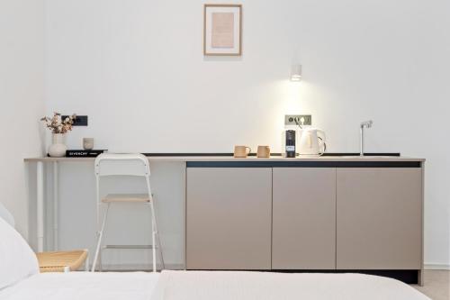 a white kitchen with a counter and a chair at Bugabu Ljubljana in Ljubljana