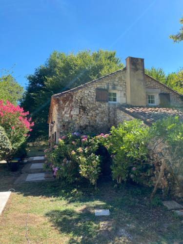 une vieille maison en pierre avec des fleurs devant dans l'établissement Cottage avec piscine la clairière des secrètes, à Saint-Jean-dʼEstissac