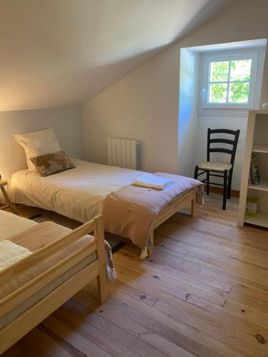 une chambre avec deux lits et une chaise dans l'établissement Cottage avec piscine la clairière des secrètes, à Saint-Jean-dʼEstissac