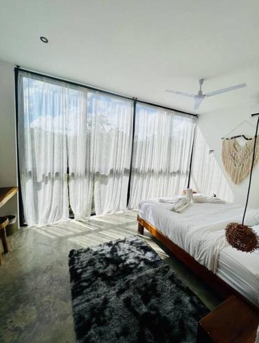a bedroom with a bed and a large window at Lush Tulum Jungle Penthouse with Ensuite Rooftop Pool & HighSpeed Wifi in Balcheil
