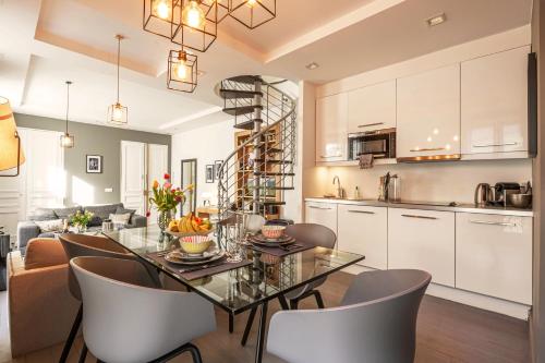 une cuisine et une salle à manger avec une table et des chaises en verre dans l'établissement 1min Walk From Champs Elysées - Avenue Montaigne - AC - Self-Checkin - Working Desk, à Paris