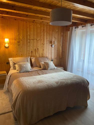 un grand lit dans une chambre aux murs en bois dans l'établissement Appartements en Montagnes, à Aime La Plagne
