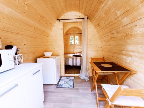 - une petite cuisine avec un réfrigérateur et une table dans une cabine dans l'établissement Chalet insolite pour 2 au coeur de la Bretagne, à Saint-Jacut-les-Pins
