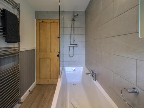 ein Badezimmer mit Badewanne und Holztür in der Unterkunft Brook Cottage in Windermere