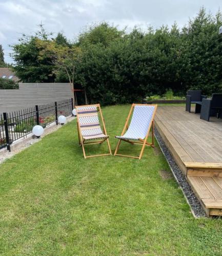 two chairs sitting on the grass next to a wooden deck at Langdale Lodge in Inverness