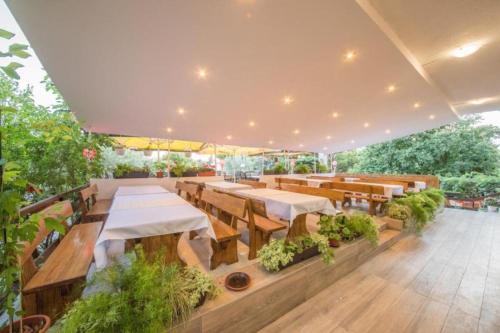 a restaurant with wooden tables and benches and plants at Hotel Riviera, Starigrad Paklenica in Starigrad-Paklenica