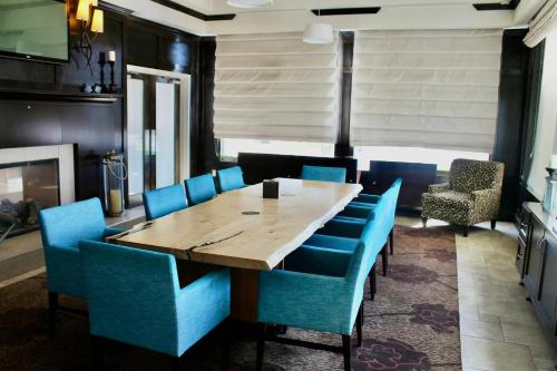 a dining room with a wooden table and blue chairs at Hilton Garden Inn Edmonton International Airport in Leduc