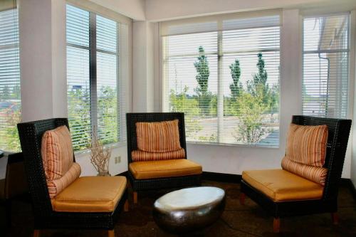 two chairs and a table in a room with windows at Hilton Garden Inn Edmonton International Airport in Leduc