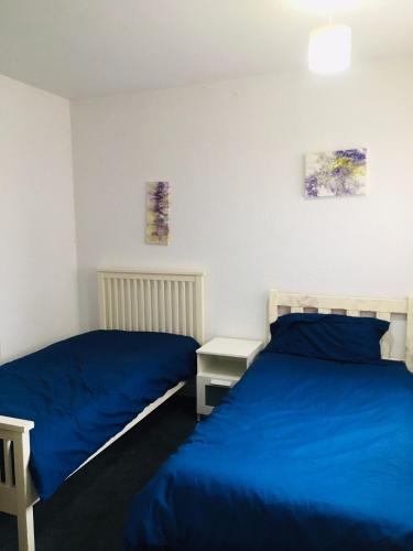 two beds in a bedroom with blue sheets at Hagley Road West House in Birmingham