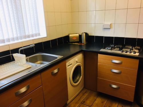 a kitchen with a sink and a washing machine at Hagley Road West House in Birmingham