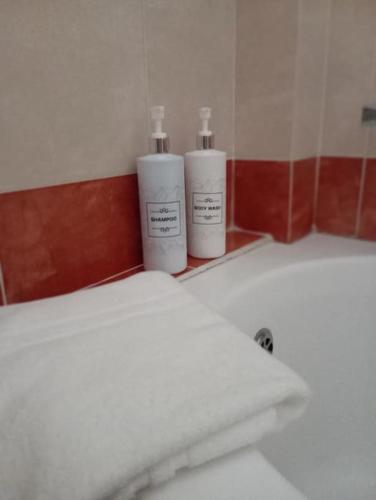 two bottles ofodorizers sitting on a shelf next to a bed at Welina guesthouse in Volos