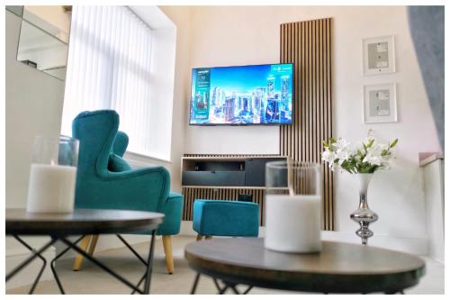 a living room with green chairs and a tv on a wall at The Grandeur Mill in Bradford