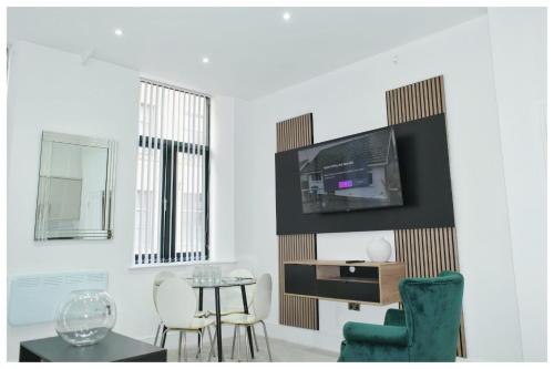 a living room with a table and a tv on a wall at The Grandeur Mill in Bradford