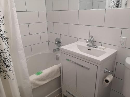 a white bathroom with a sink and a bath tub at Almo Court Motel in Cranbrook