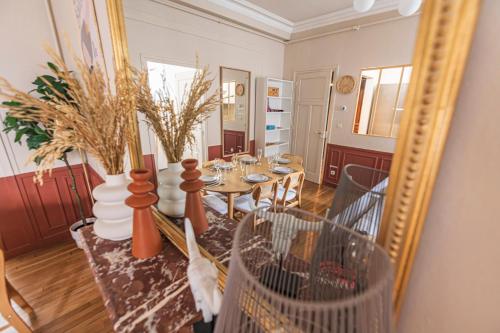 une salle à manger avec une table et un miroir dans l'établissement L'haussmannien - Spacieux 4 chambres - Centre - Gare, à Reims