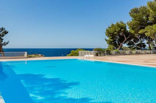 une piscine bleue avec l'océan en arrière-plan dans l'établissement Studio Bord de mer cadre exceptionnel, à Bandol