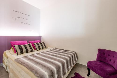 une chambre avec un lit et une chaise violette dans l'établissement Parata, à Ajaccio