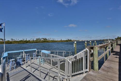 a dock with chairs on it next to the water at 2-2 Riverfront Condo At Bouchelle Island in New Smyrna Beach