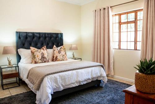 a bedroom with a large bed with a black headboard at Camderest House in Graaff-Reinet