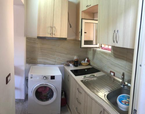 a small kitchen with a washing machine and a sink at Portokallja Guest House Radhime in Vlorë