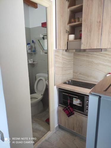a small kitchen with a stove and a toilet at Portokallja Guest House Radhime in Vlorë