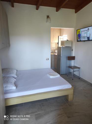a bedroom with a bed and a kitchen with a refrigerator at Portokallja Guest House Radhime in Vlorë