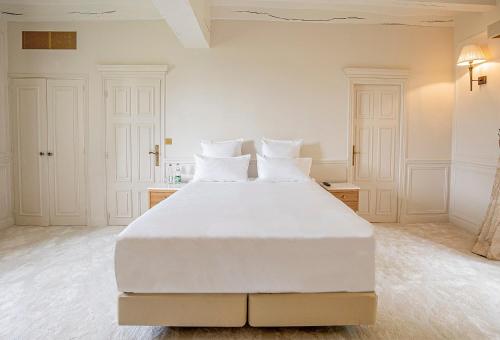 a white bedroom with a large bed with white pillows at Château De Noirieux in Briollay
