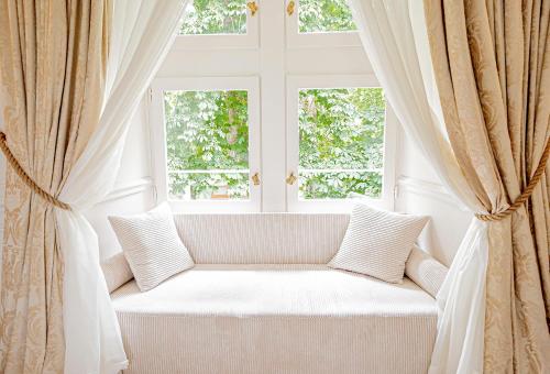 a white couch in a room with two windows at Château De Noirieux in Briollay