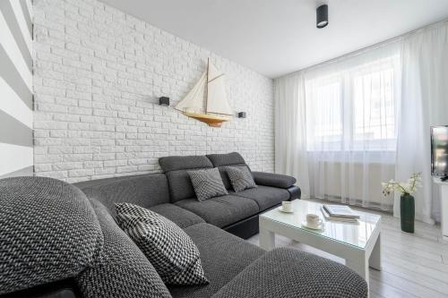 a living room with a couch and a brick wall at Apartamenty blisko morza Przy Wydmie in Darłówko