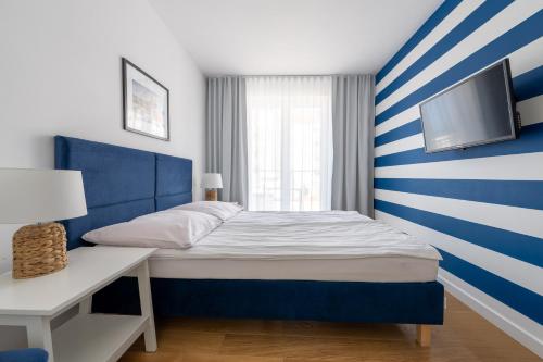 a bedroom with a blue and white striped wall at Apartamenty blisko morza Przy Wydmie in Darłówko