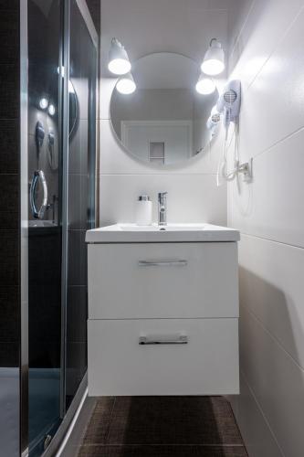 a white bathroom with a sink and a mirror at Apartamenty blisko morza Przy Wydmie in Darłówko