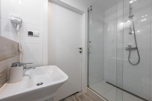 a white bathroom with a shower and a sink at Apartamenty blisko morza Przy Wydmie in Darłówko