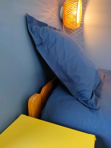 a blue pillow sitting on a bed with a yellow table at Le Duplex du Plongeoir - spacieux T3 de 65m2 avec vue sur le lac de Serre Ponçon in Savines