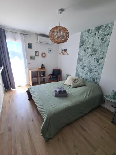a bedroom with a bed with a green comforter at Le Petit Chêne in Orgnac-lʼAven
