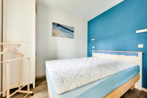 une chambre avec un lit avec un mur bleu dans l'établissement Port du Crouesty Cap'Océan - maeva Home - Appartement 2 pièces 4 personnes vue sur le port - Sélection MAE-9421, à Arzon