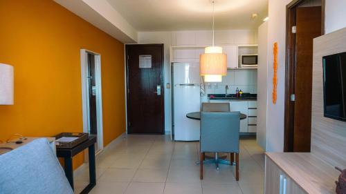 a kitchen with yellow walls and a table and a chair at Beach Class Convention - Flats em Boa Viagem por Yolo in Recife