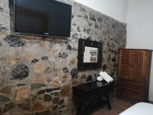 a room with a stone wall with a flat screen tv at Grann Posada Xilitla in Xilitla