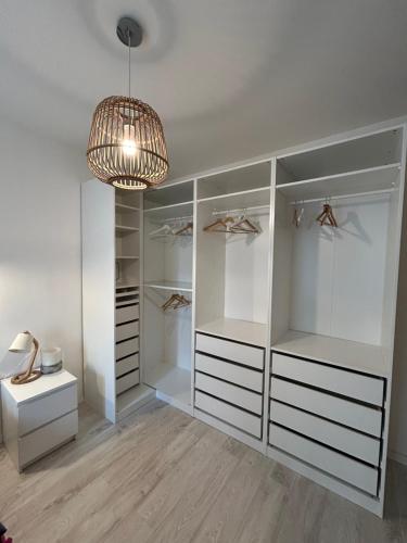 Elle comprend un dressing avec des placards blancs et un lustre. dans l'établissement Charmante Maison de Village, à Saint-Laurent-des-Arbres