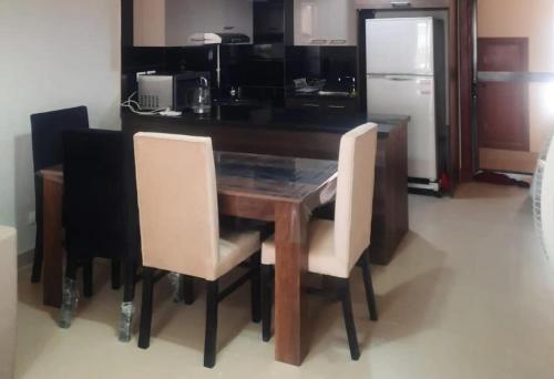 cocina con mesa de madera con sillas y nevera en Whispering Waters Two Bedroom with a Garden Azha, en Ain Sokhna