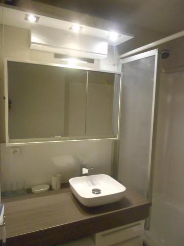 une salle de bain avec un lavabo et un miroir dans l'établissement Green Village, à La Grande Motte