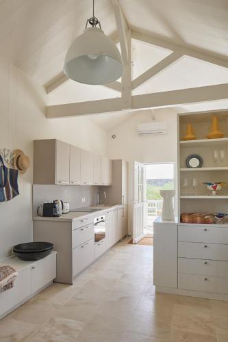 une cuisine avec des placards blancs et un grand plafond dans l'établissement MAISON SUR LA PLAGE avec VUE MER PANORAMIQUE, à Le Martray