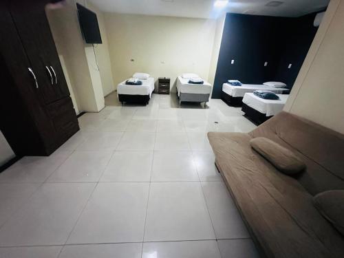 a room with three beds and a couch in it at Hotel St. Daniel in Guarulhos
