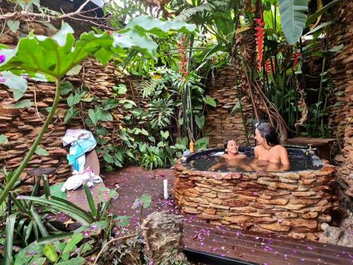 a man and woman in a bath tub in a garden at Casa jardim com ofurô - Chapada dos veadeiros in Cavalcante