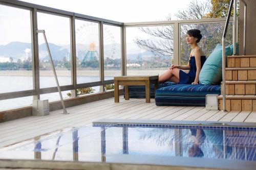 a woman sitting on a couch next to a swimming pool at Ako Onsen Shokichi in Ako